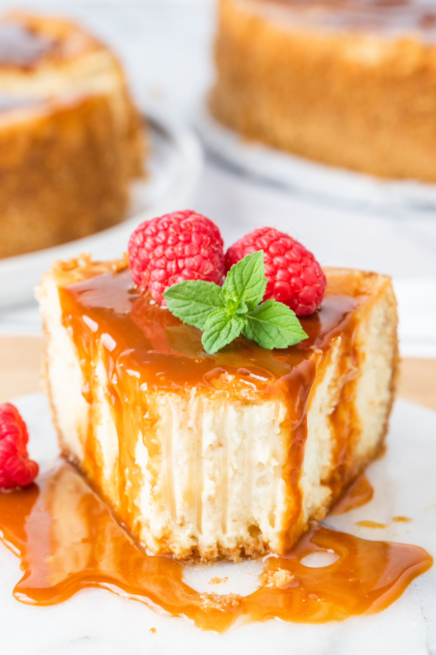 slice of caramel cheesecake topped with caramel sauce, and topped with fresh berries and mint