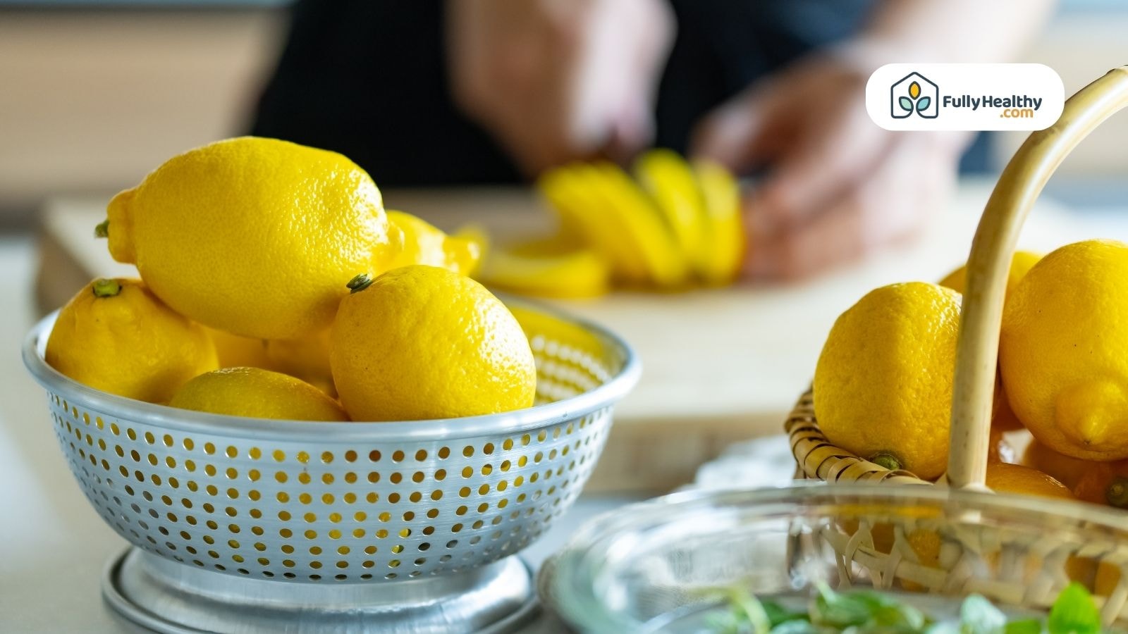 Whole lemons in a metal colander with sliced lemon wedges