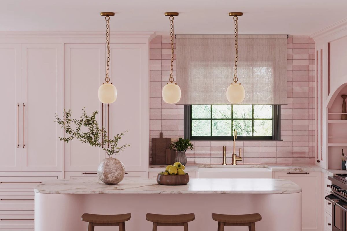 Pendant light trio in a statement making design displayed over a white kitchen island with brass fixtures and airy modern style.