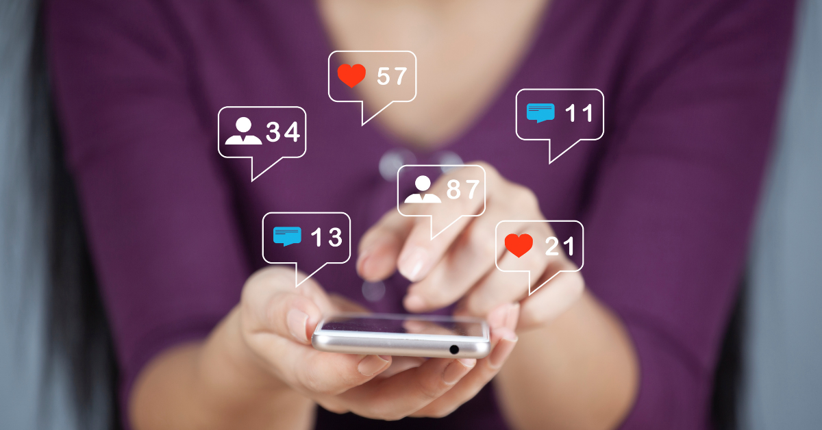 Someone holding a phone with various social media marketing notifications appearing.