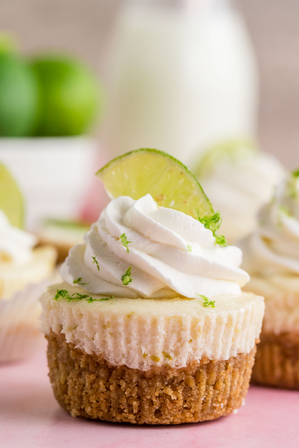 mini key lime cheesecake topped with whipped cream and slice of lime
