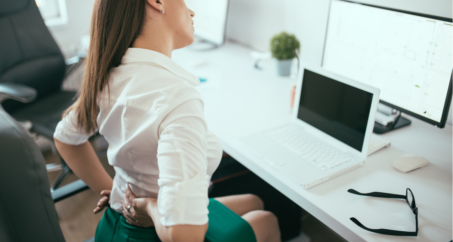 woman with back pain and muscle tension on a office chair