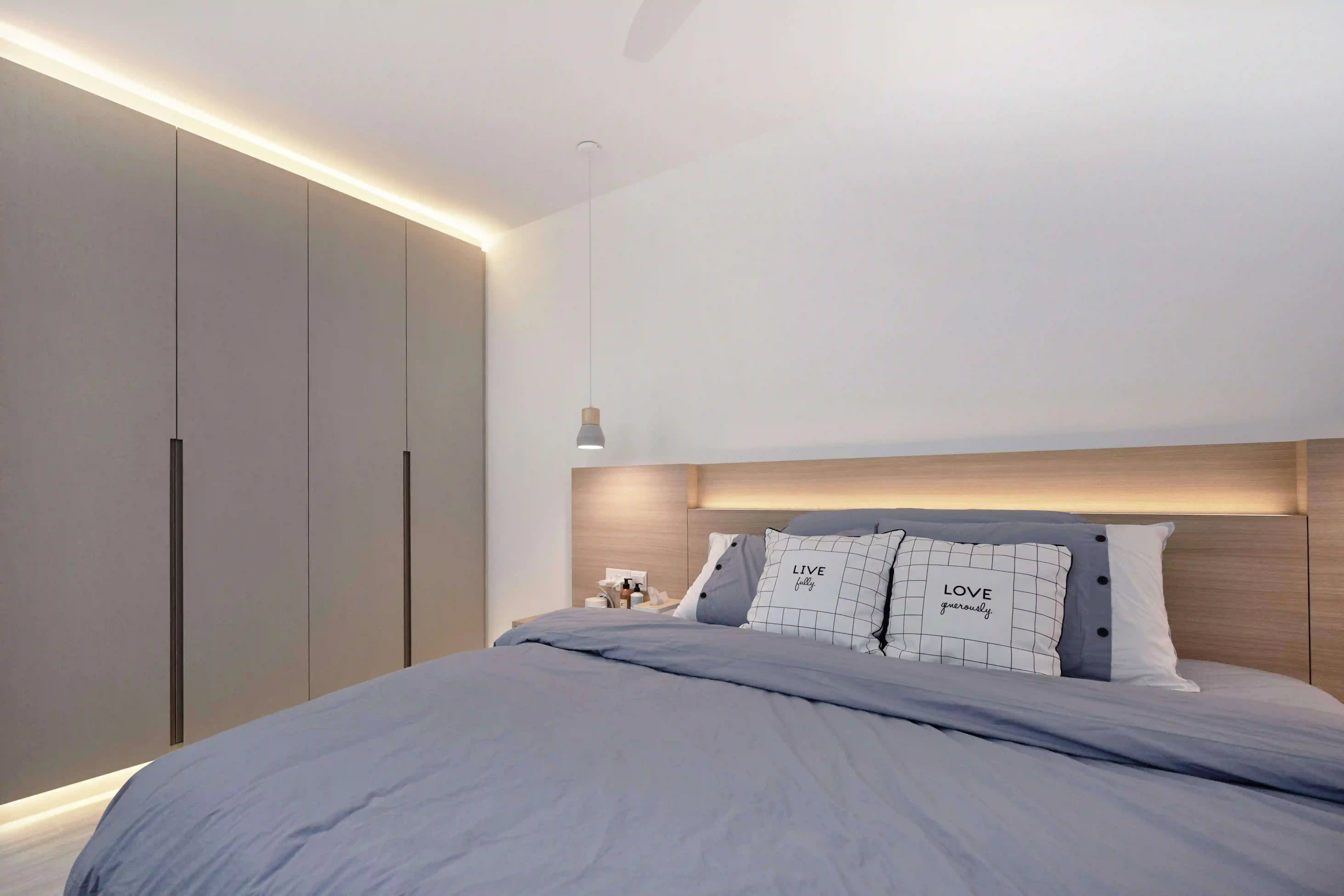 Minimalist room with built-in wardrobe, warm headboard lighting and a slim pendant beside the bed