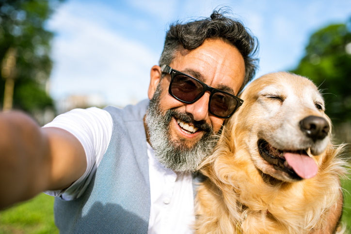 Mature man in sunglasses with his Golden retriever. 