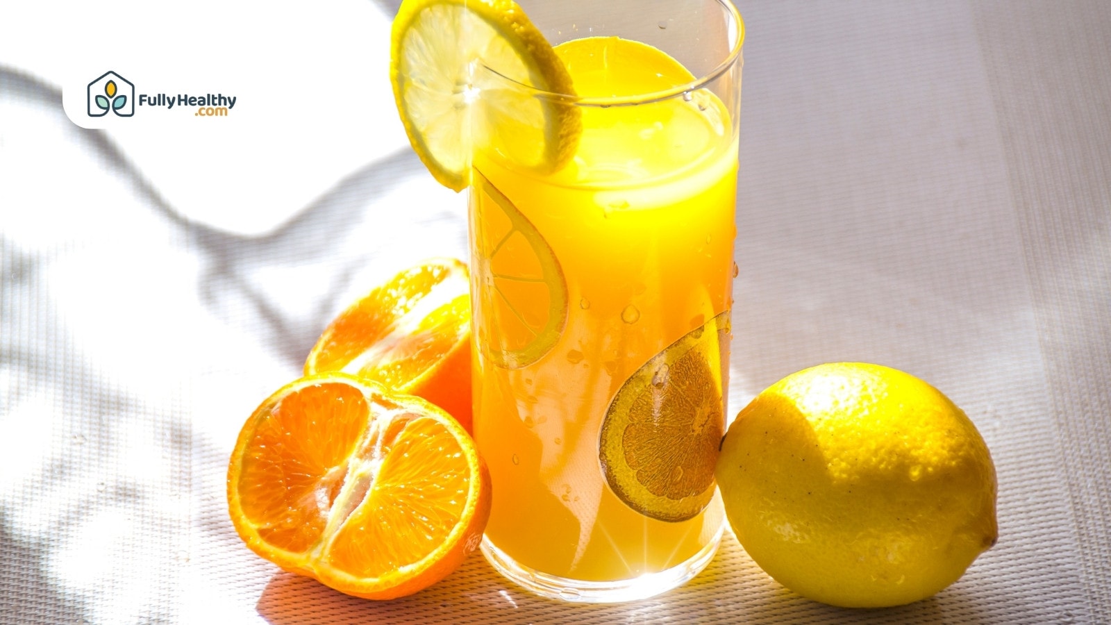 Refreshing citrus juice in glass with lemon slice and fresh oranges