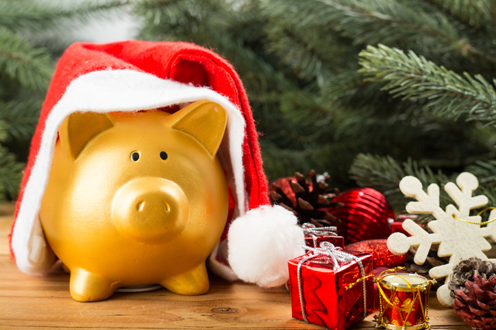 Gold piggy bank draped with a Santa cap.