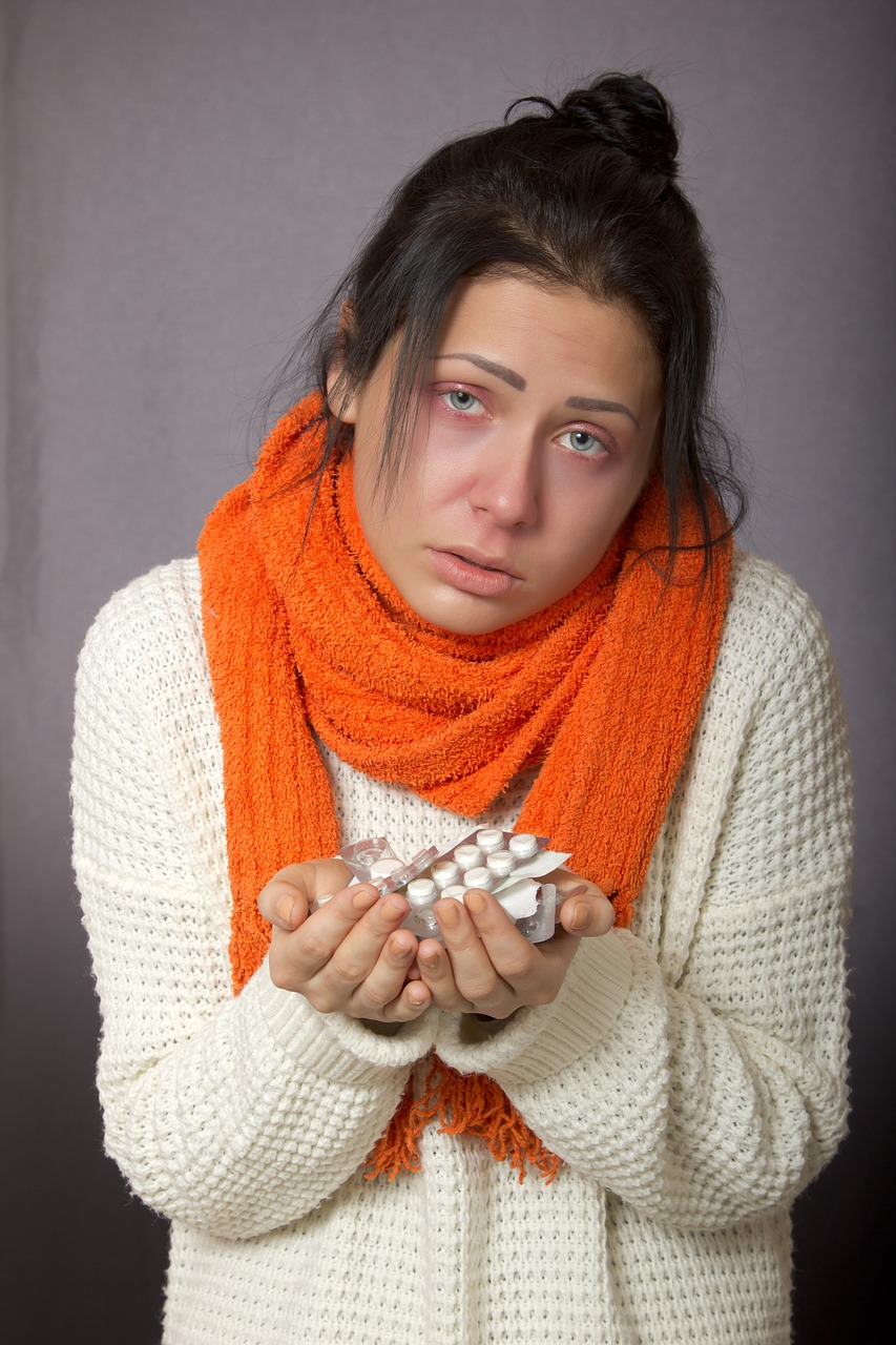 An image of a sick young woman with allergies holding packets of antihistamines.
