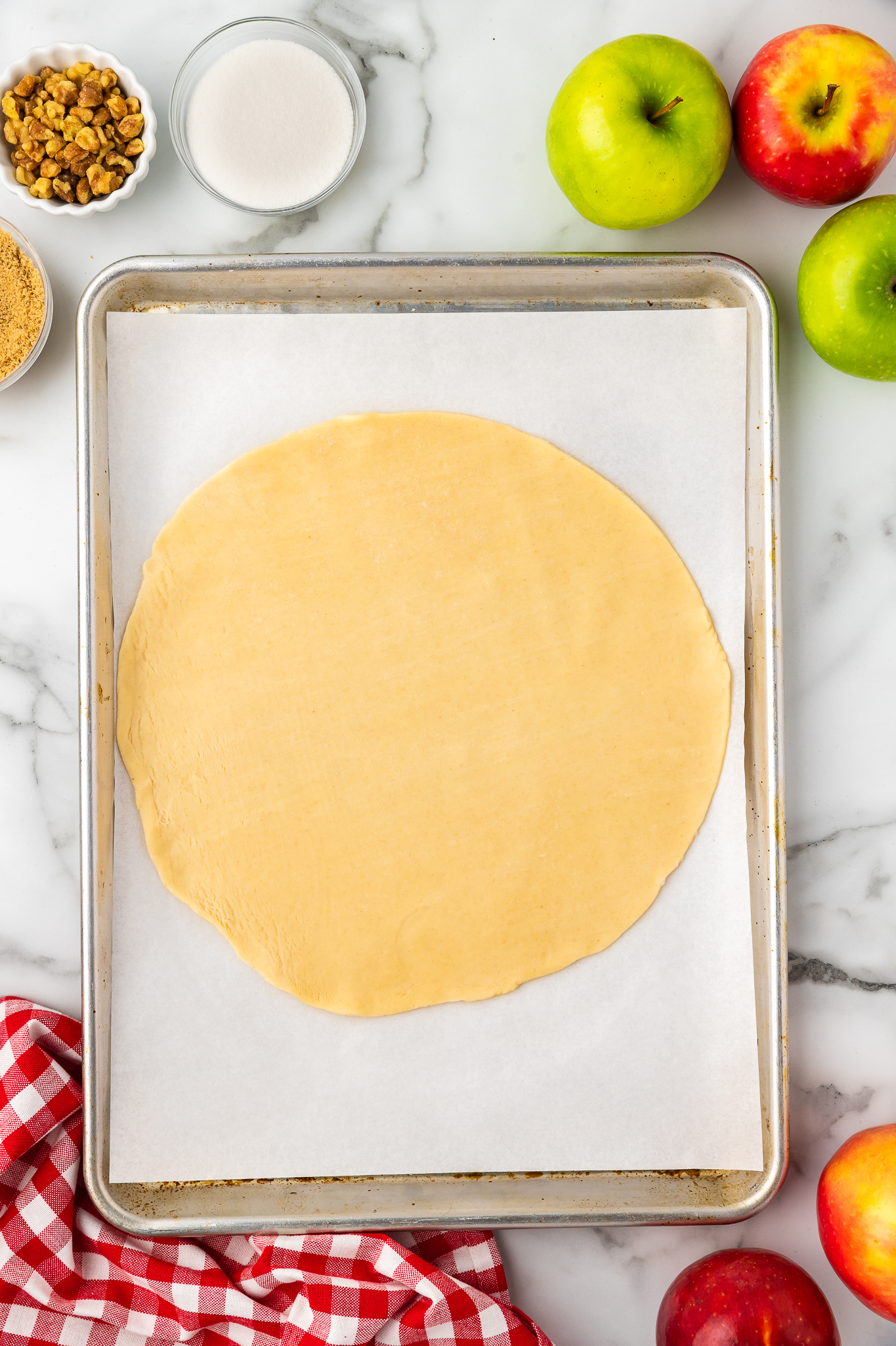 pie dough rolled out into a circle on a baking sheet lined with parchment paper