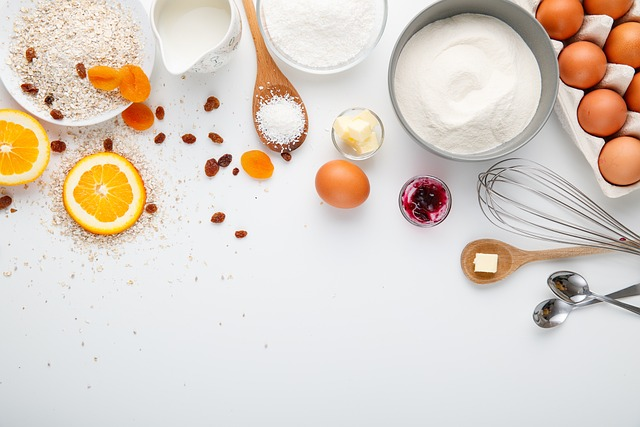 An image of chicken eggs, oats, orange slices, flour, and other cooking ingredients on a table.