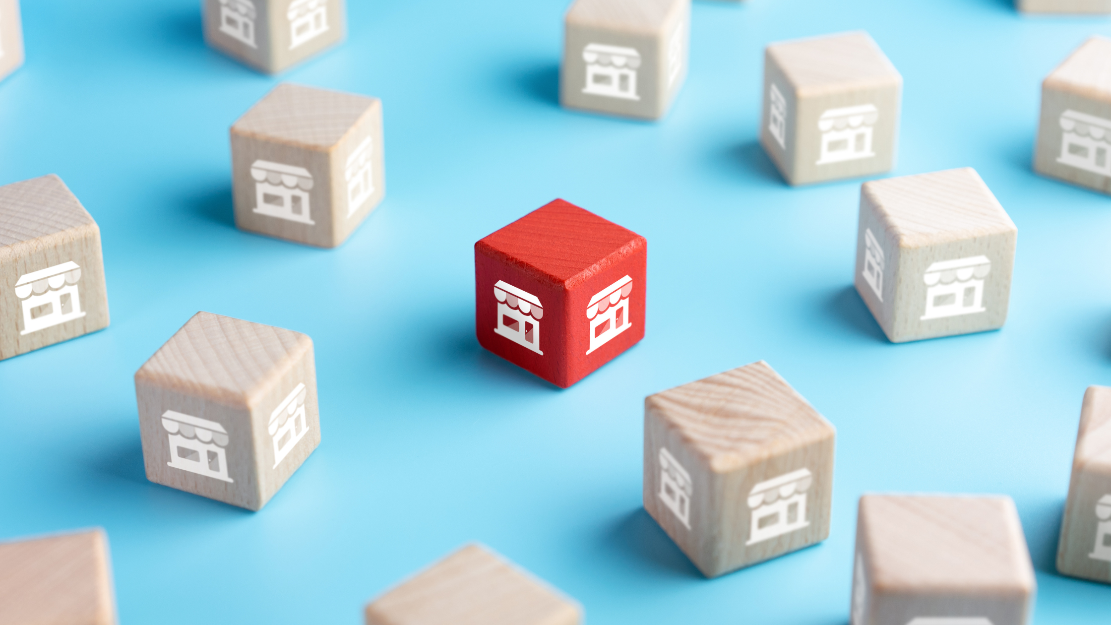 Red cube with storefront icon among neutral ones, representing how range, control, and cable limitations affect multi-site connectivity without enterprise-grade technology.