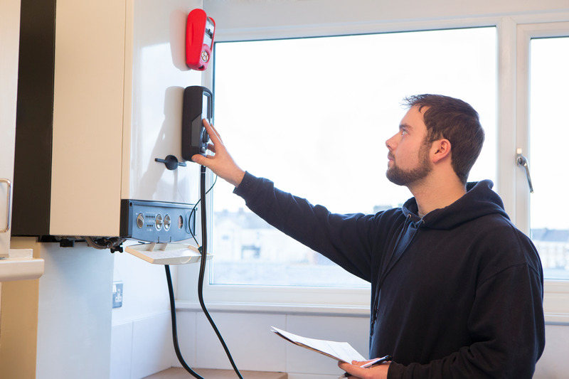 Techniker überprüft Heizthermostat in modernem Wohnraum.