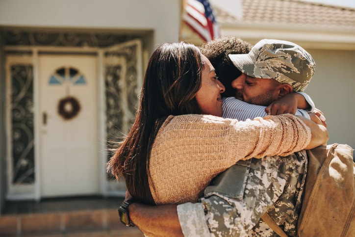 Military family hugging at the front door.