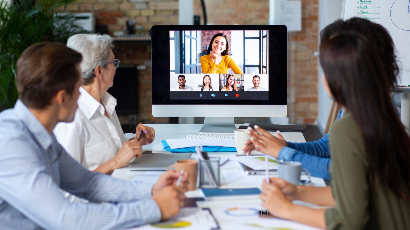Office team watching a video call with six participants on a large screen, demonstrating Collab 2.0’s teamwork and communication features.
