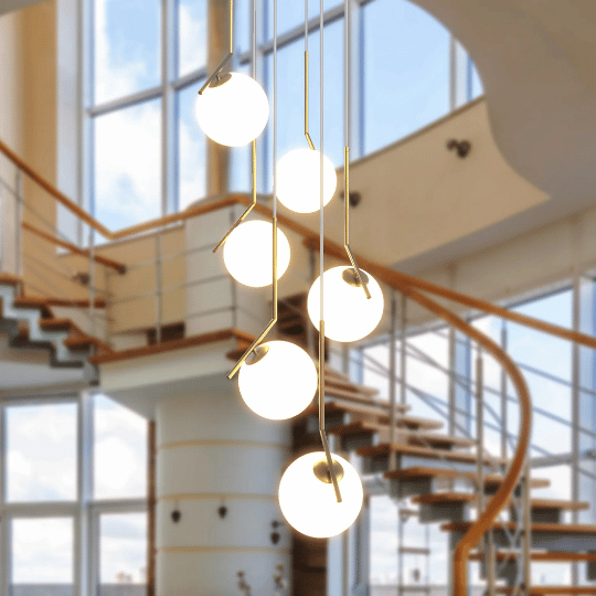 Modern pendant chandelier featuring cascading frosted glass globes on gold rods, creating a sculptural focal point in a contemporary foyer.