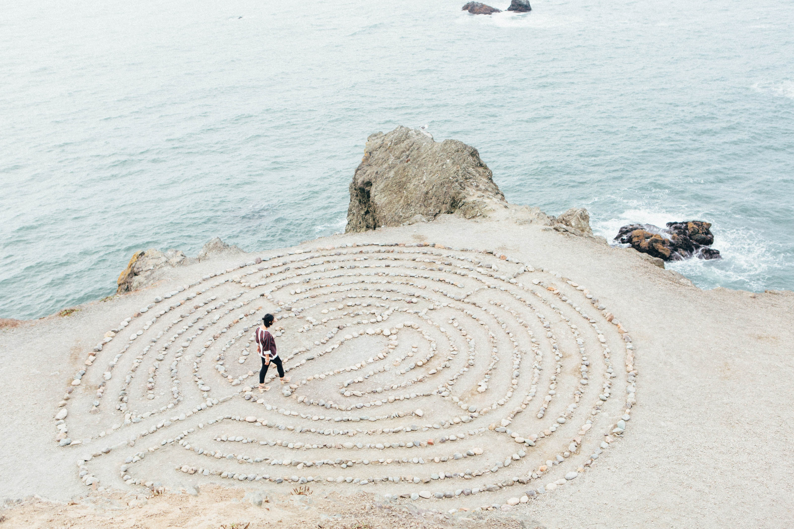 man walking in a sand maze on the beach