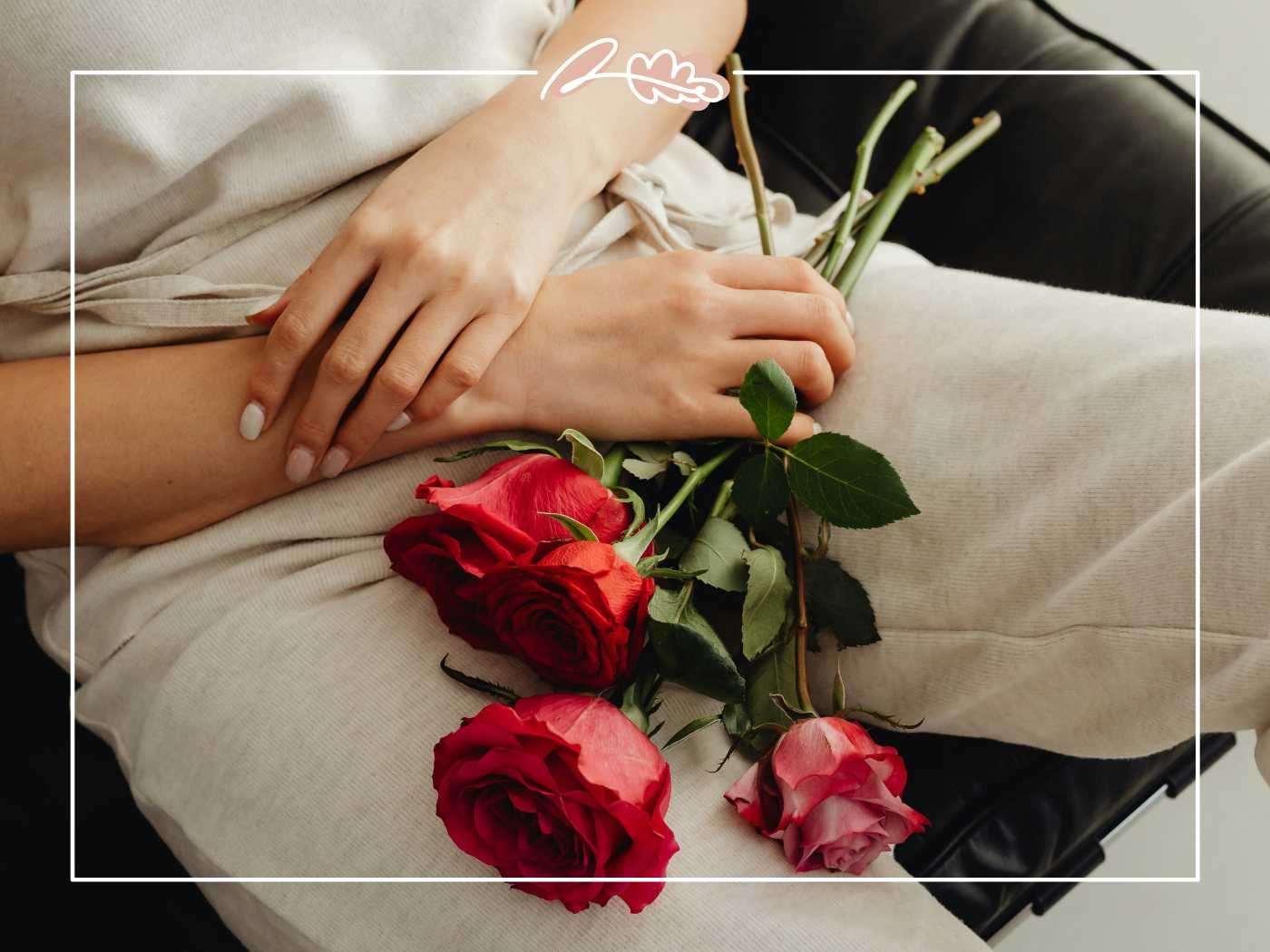 A person relaxing on a couch, holding red roses in their lap, symbolising love and comfort - Fabulous Flowers and Gifts.