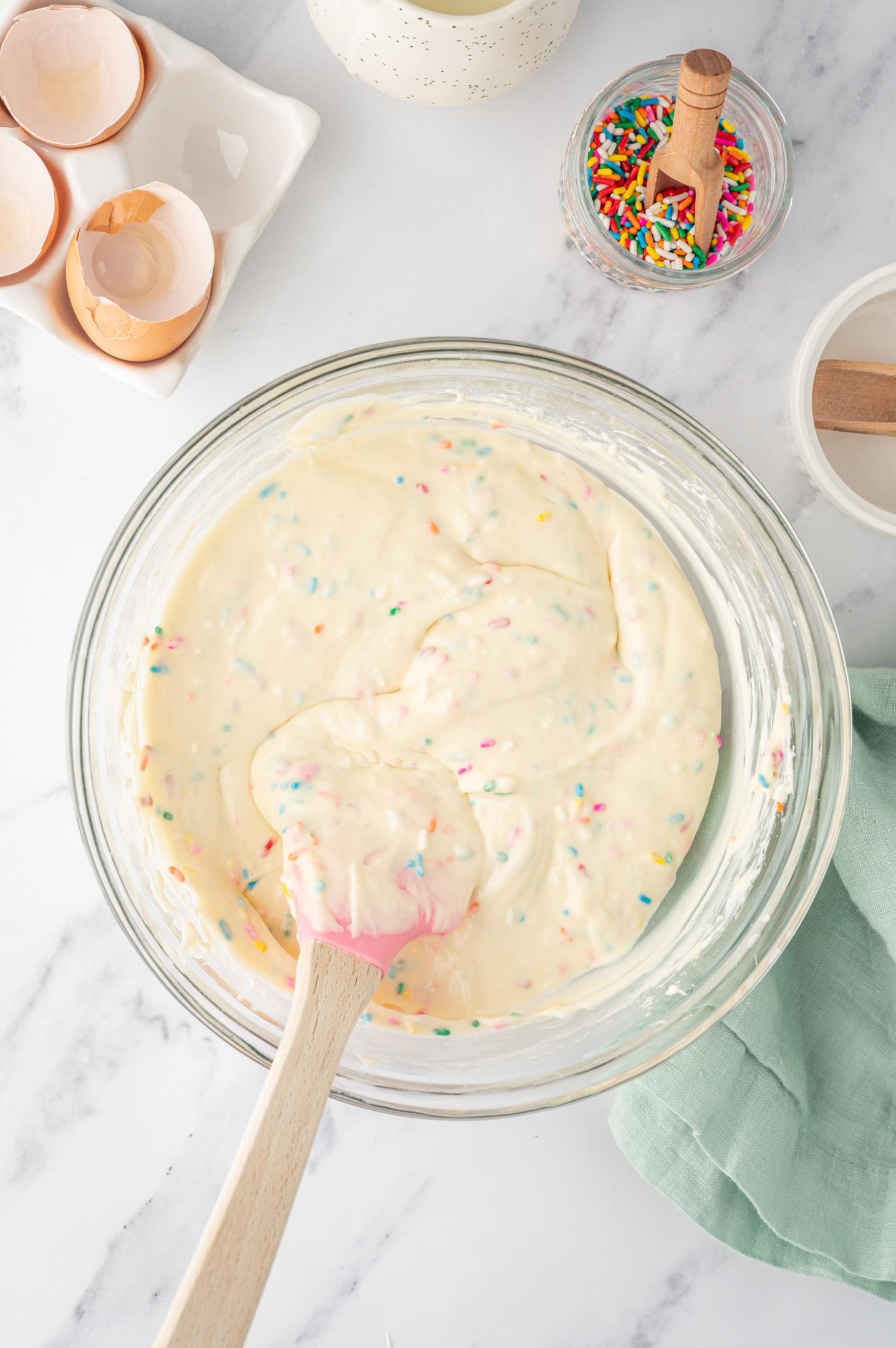 rainbow sprinkles folded into cheesecake filling with rubber spatula
