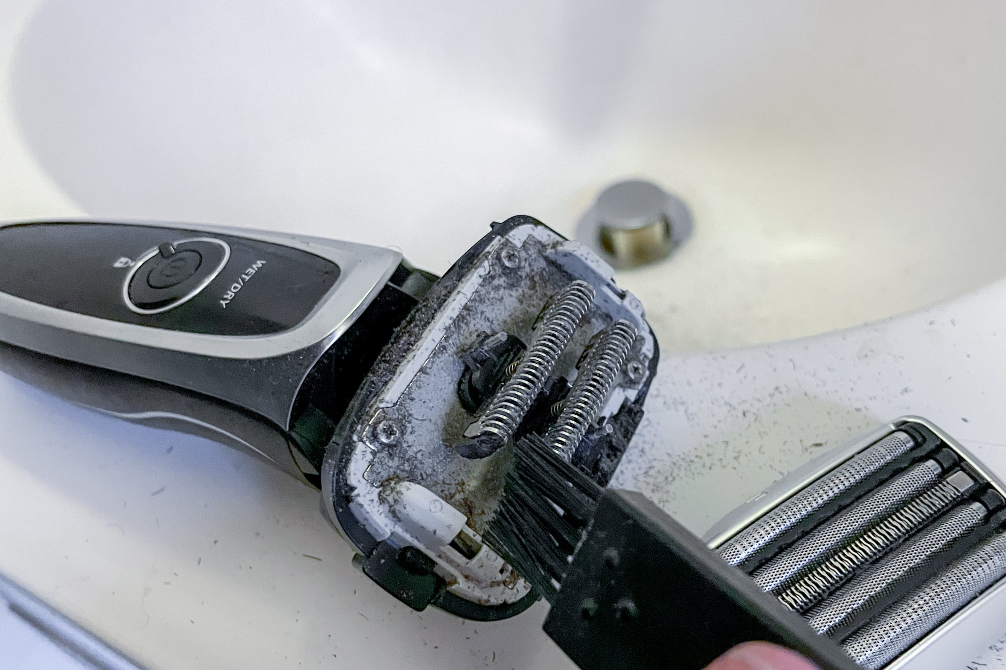 A person cleaning an electric shaver