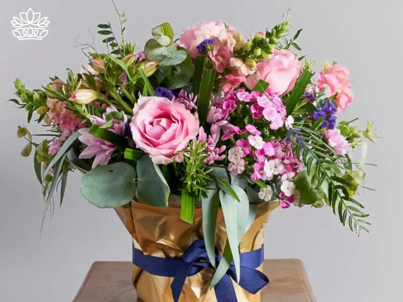 Vibrant bouquet of pink roses, purple lilies, and assorted blooms wrapped in golden paper with a blue ribbon, perfect as get well flowers. Delivered with Heart. Fabulous Flowers and Gifts.