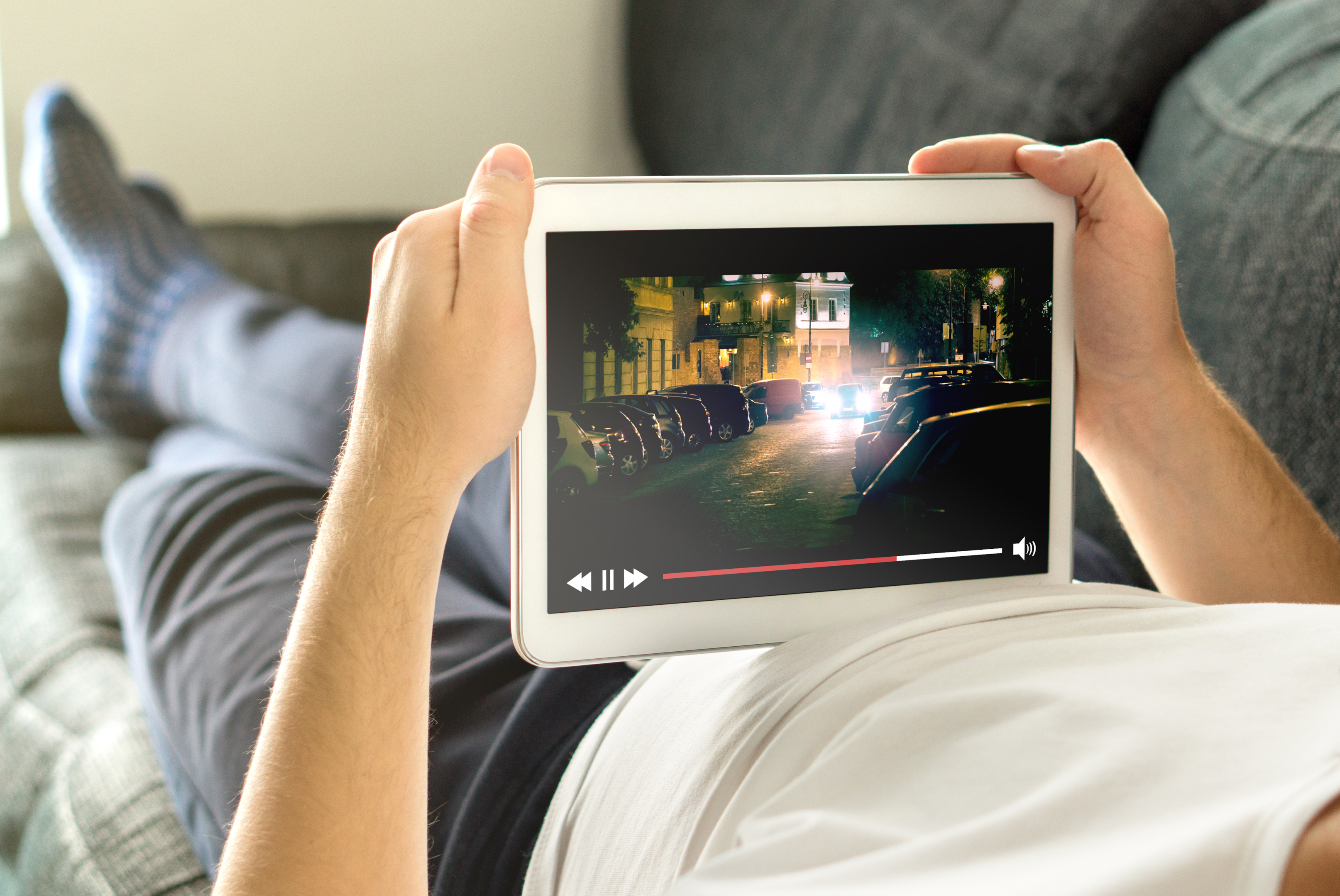 a man lays down on his couch while streaming a tv show on his tablet