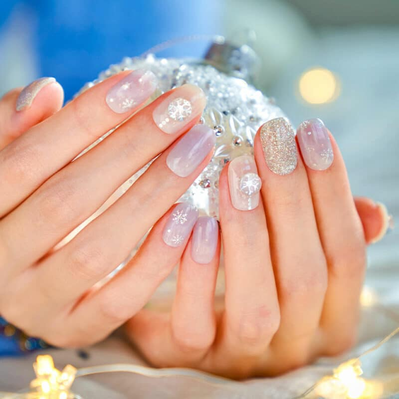 Christmas theme manicure Womans hand in fingerless puffy gloves holding a christmas bauble holiday nails stock pictures, royalty-free photos & images
