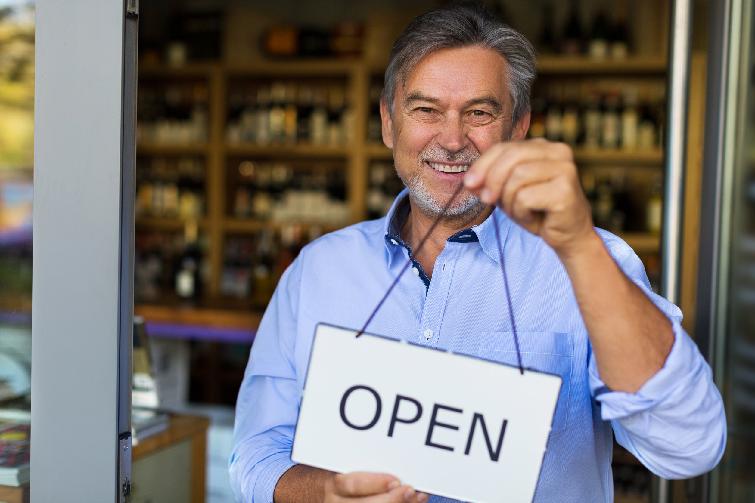 small business owner holding open sign for shop