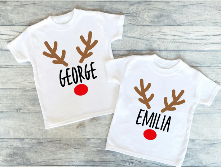 white Christmas outfits with reindeer antlers and a bright red nose. Custom name printed in the middle