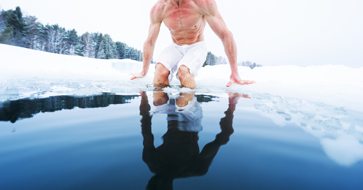 A photograph of a man dipping into a frozen lake for a natural ice bath.