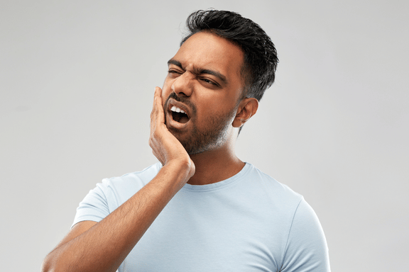 male holding jaw in pain in need of upper and lower jaw surgery