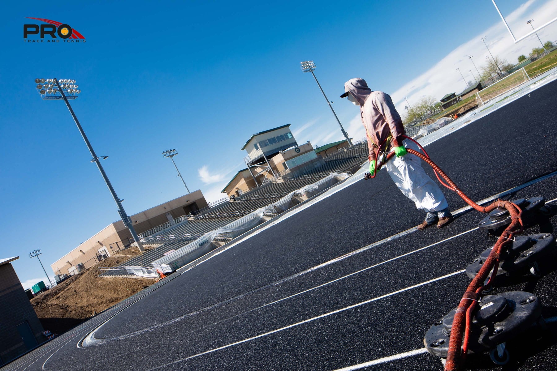 Pro Track & Tennis crew working on a running track installation, preparing the base layer and applying new surfacing material for a durable and high-performance finish.