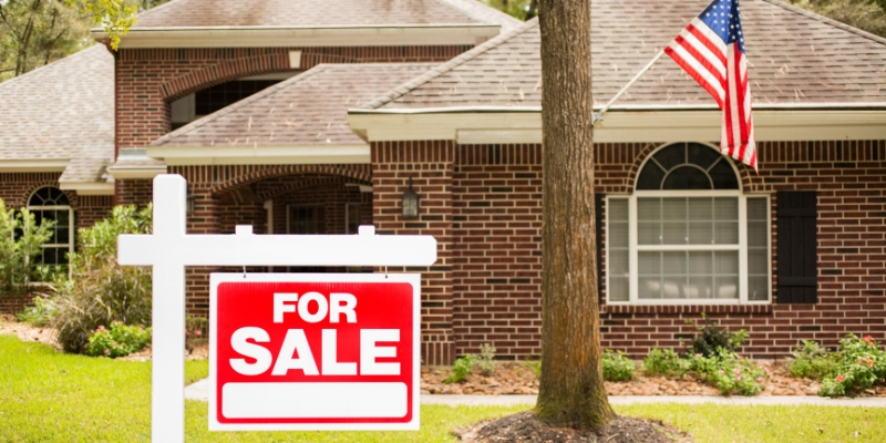 A photo of a house with a selling house to pay off student loans sign in the front yard, representing the process of determining your home's value.