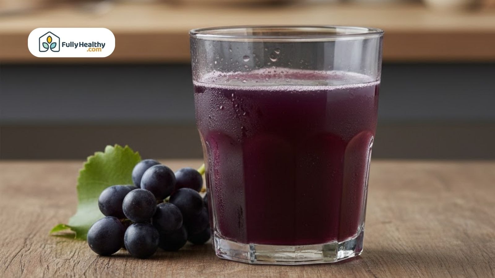 Glass of purple grape juice beside fresh grapes on a wooden table.