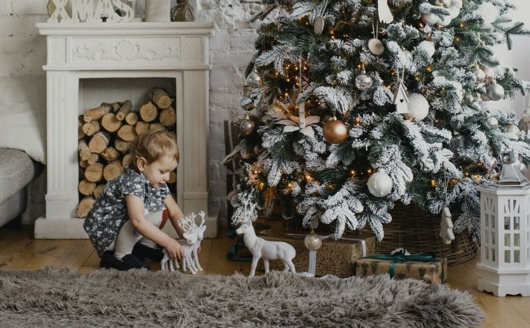 child playing with toys under christmas tree