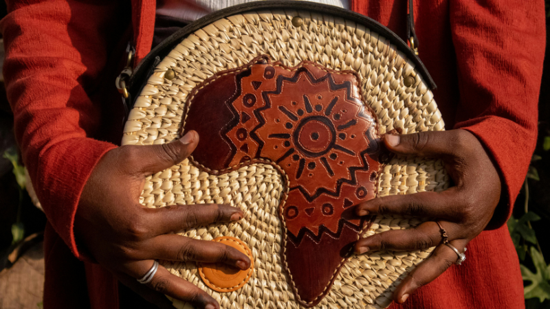 A person holding a woven basket with a design on it