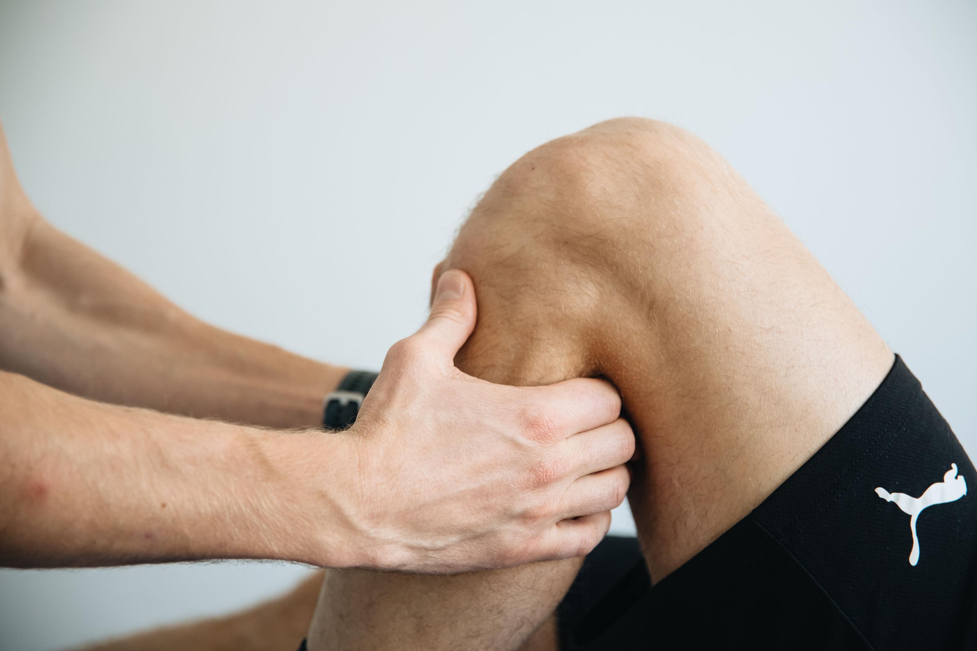 Physical therapist evaluating knee and leg injury during sports physical therapy session in Scottsdale