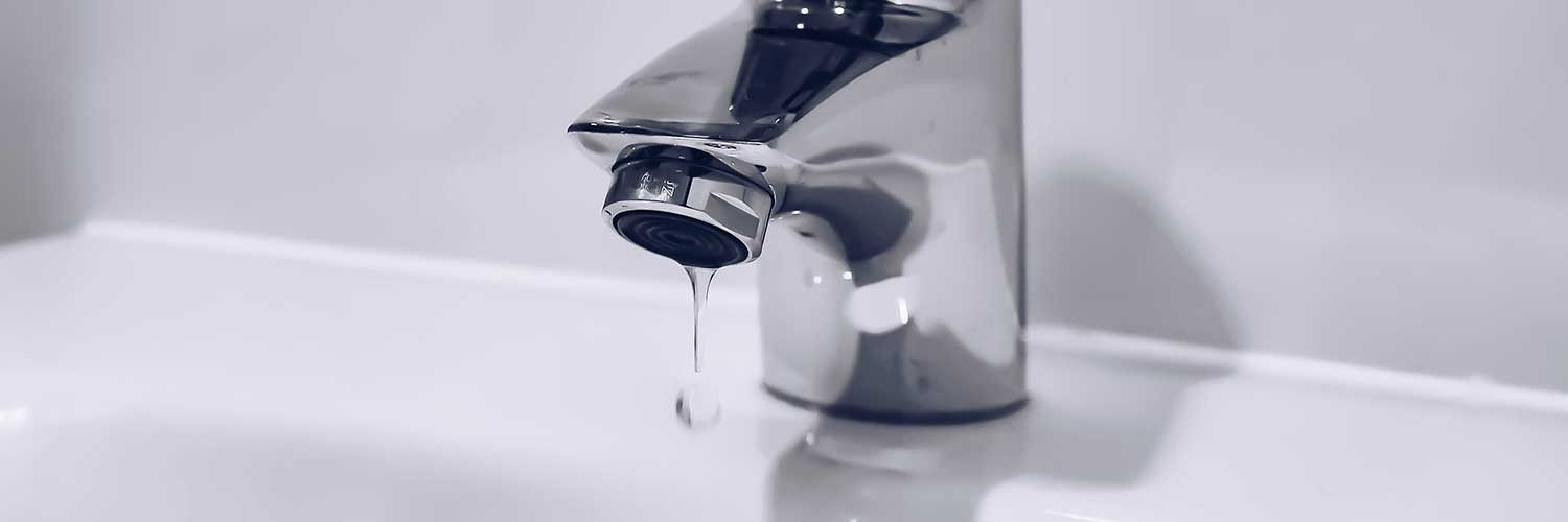 A dripping faucet with water drops falling into a sink