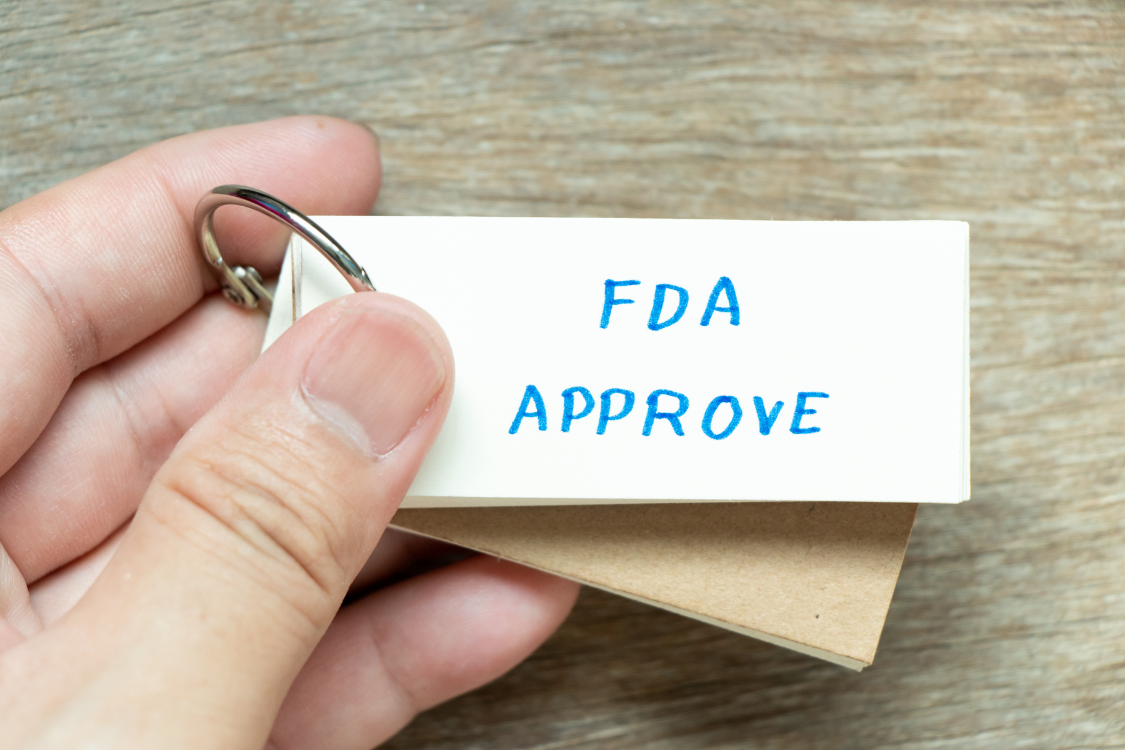 Hand holding a label reading FDA Approve, symbolizing regulatory compliance