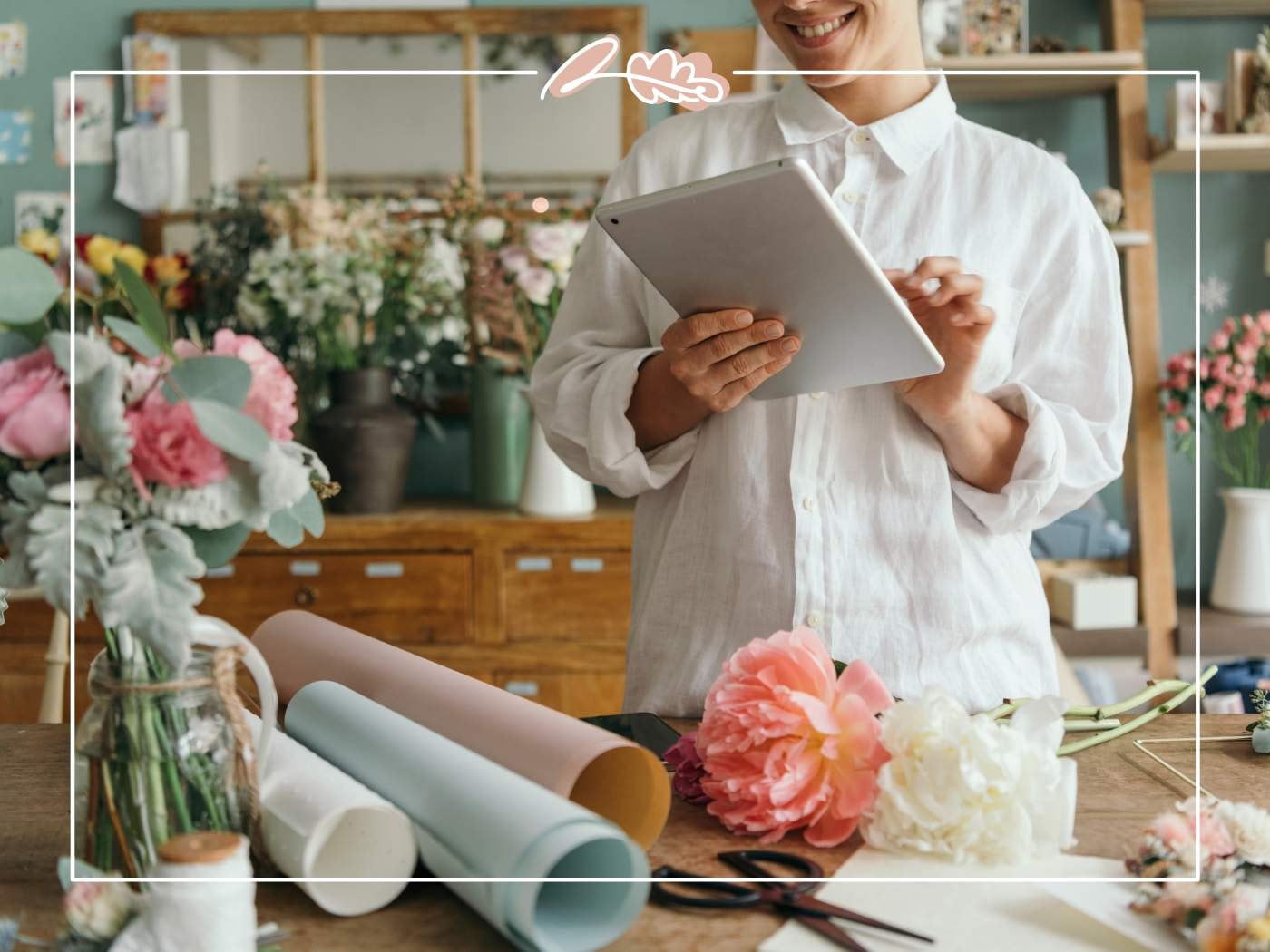 A florist smiling while working with peonies and floral supplies, featured in '11 Fabulous Reasons to Buy Peonies'.