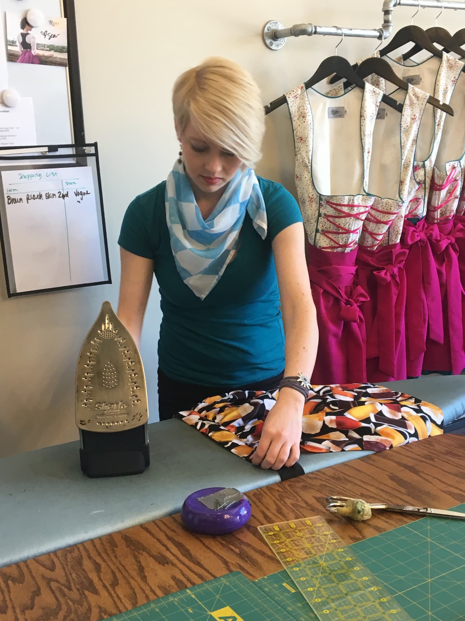 seamstress pressing garments on an iroing board careful not to ruin the materials