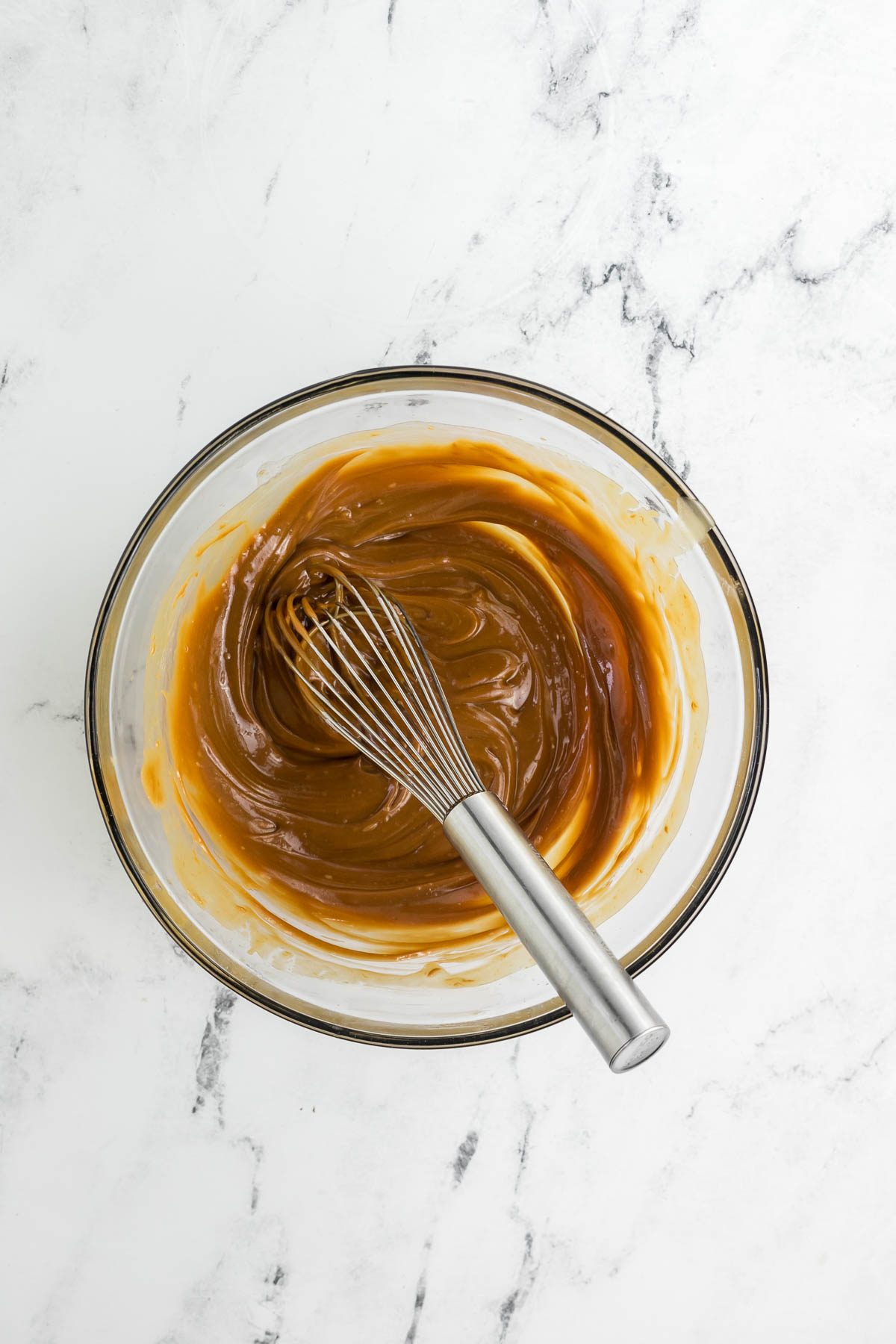 large bowl of melted butter and biscoff cookie butter spread stirred together with a whisk