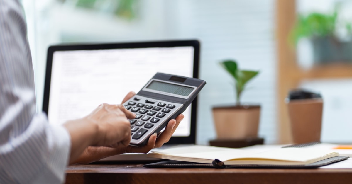 Person using a calculator at a desk, categorizing business expense categories for financial management.