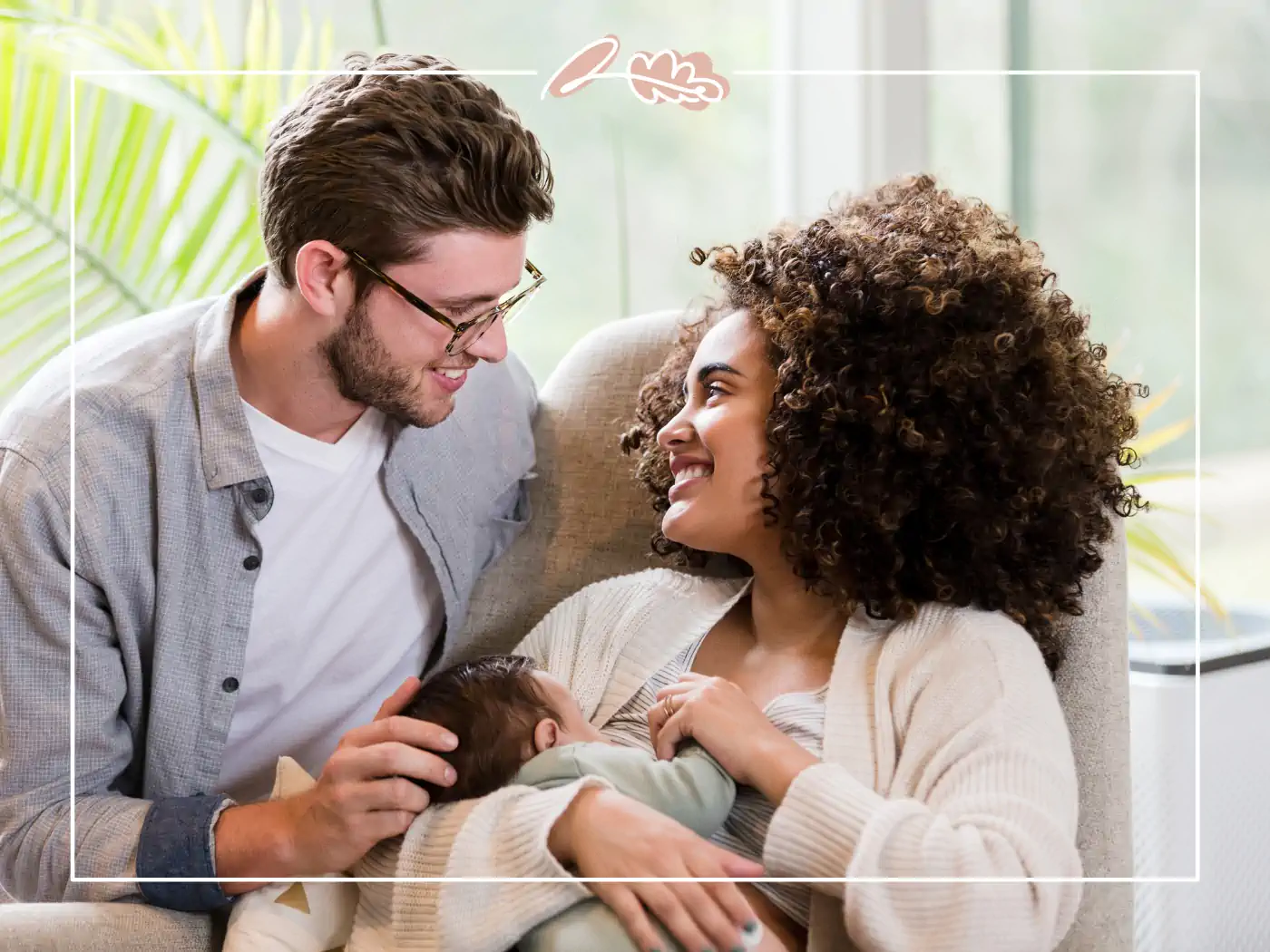 A smiling couple admiring their newborn baby, sitting together in a cozy room. Fabulous Flowers and Gifts.