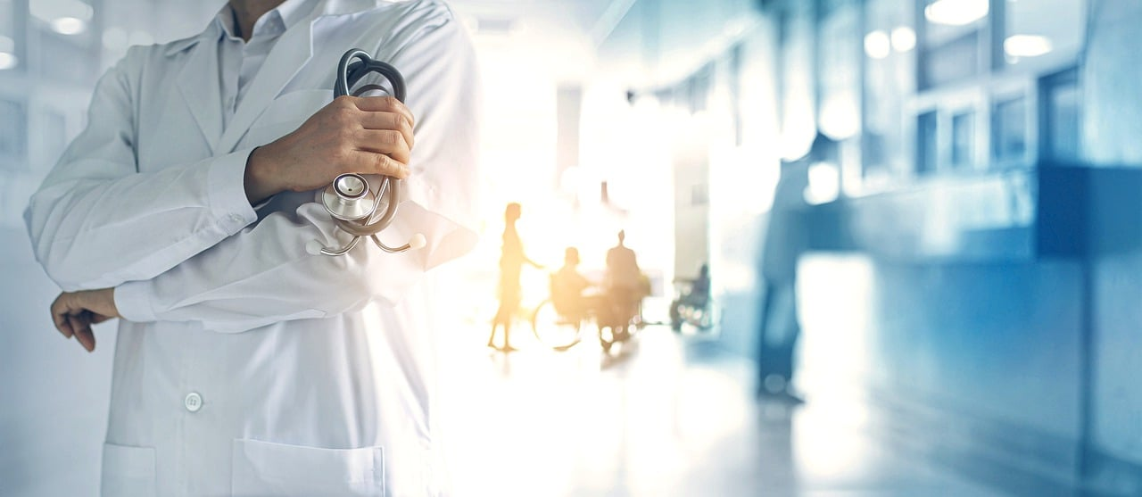 An image of a doctor standing in a hospital preparing to talk to a patient about adult tonsillectomy recovery.