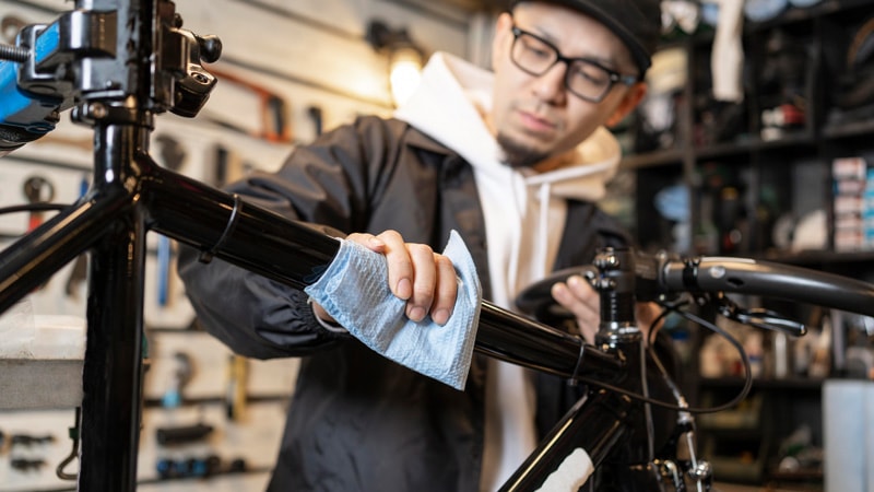 Person cleaning the glossy black bike fram with a cloth