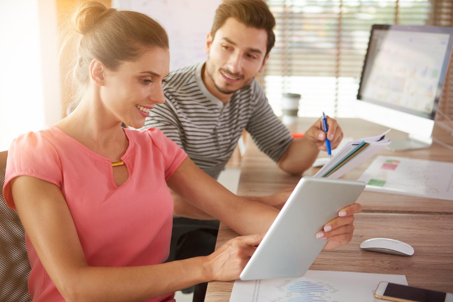 Two ecommerce store owners reviewing order and inventory information on a tablet at a desk