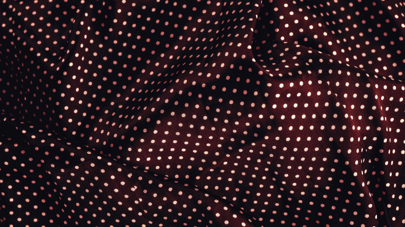 A close-up of a black and white polka dot rayon fabric