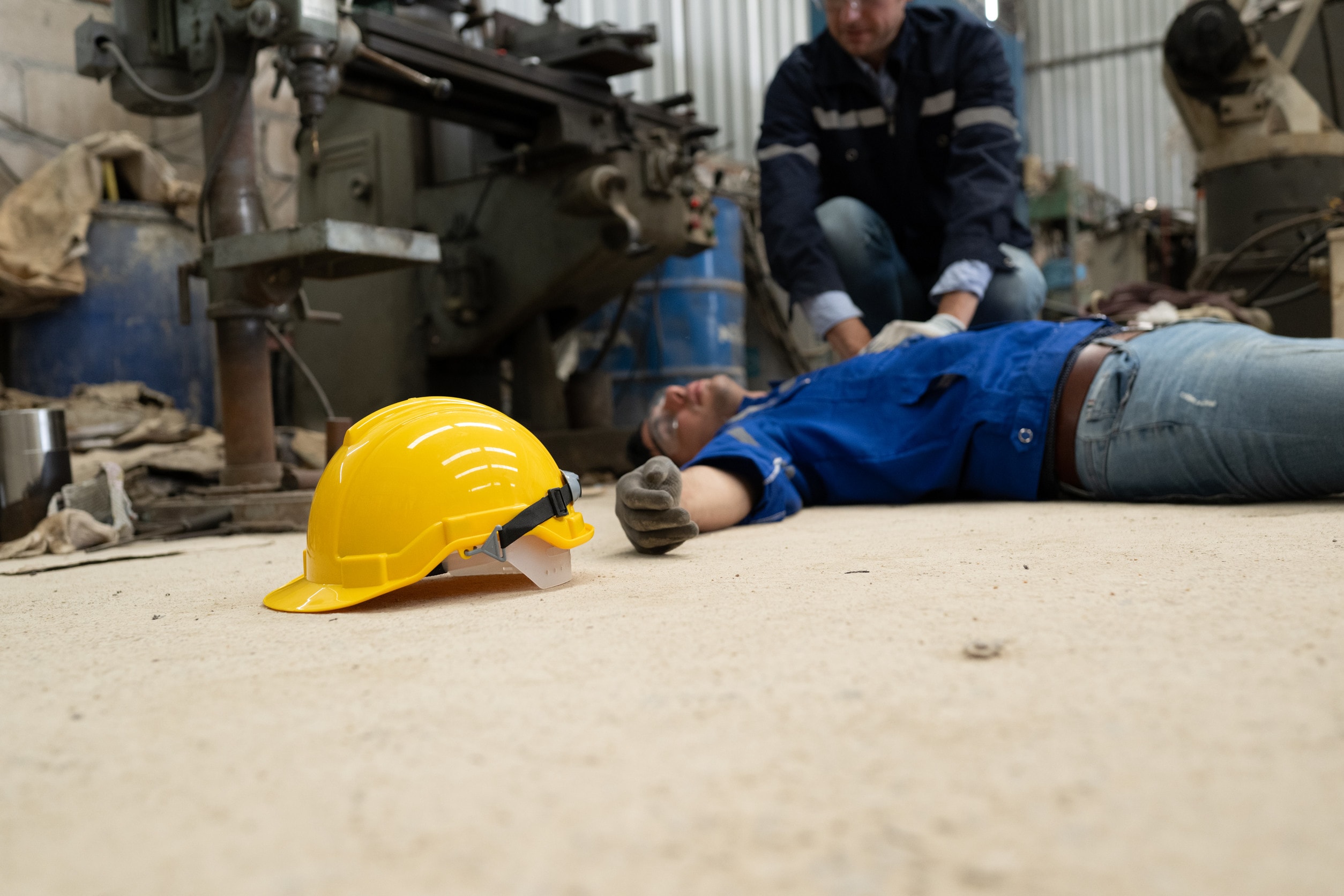 A worker lays unconscious on the ground after suffering from factory injuries.