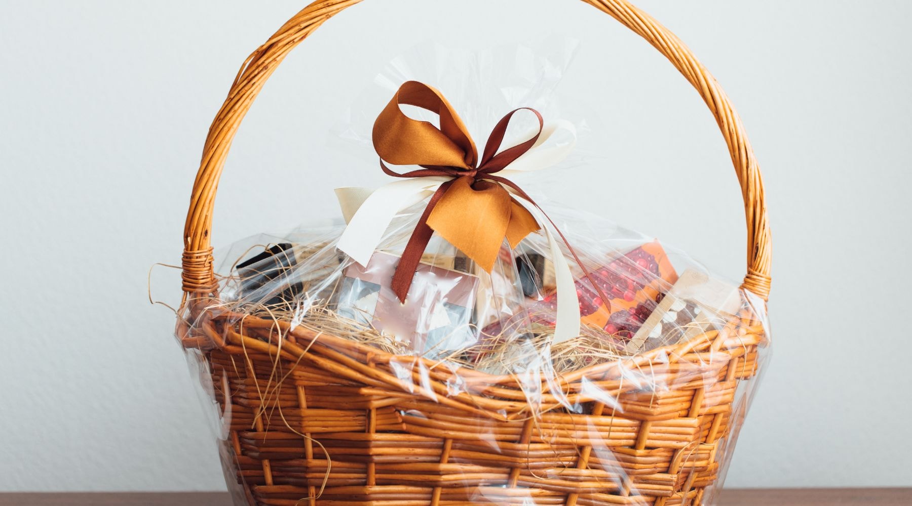 Wicker basket filled with assorted gift items and a large bow.