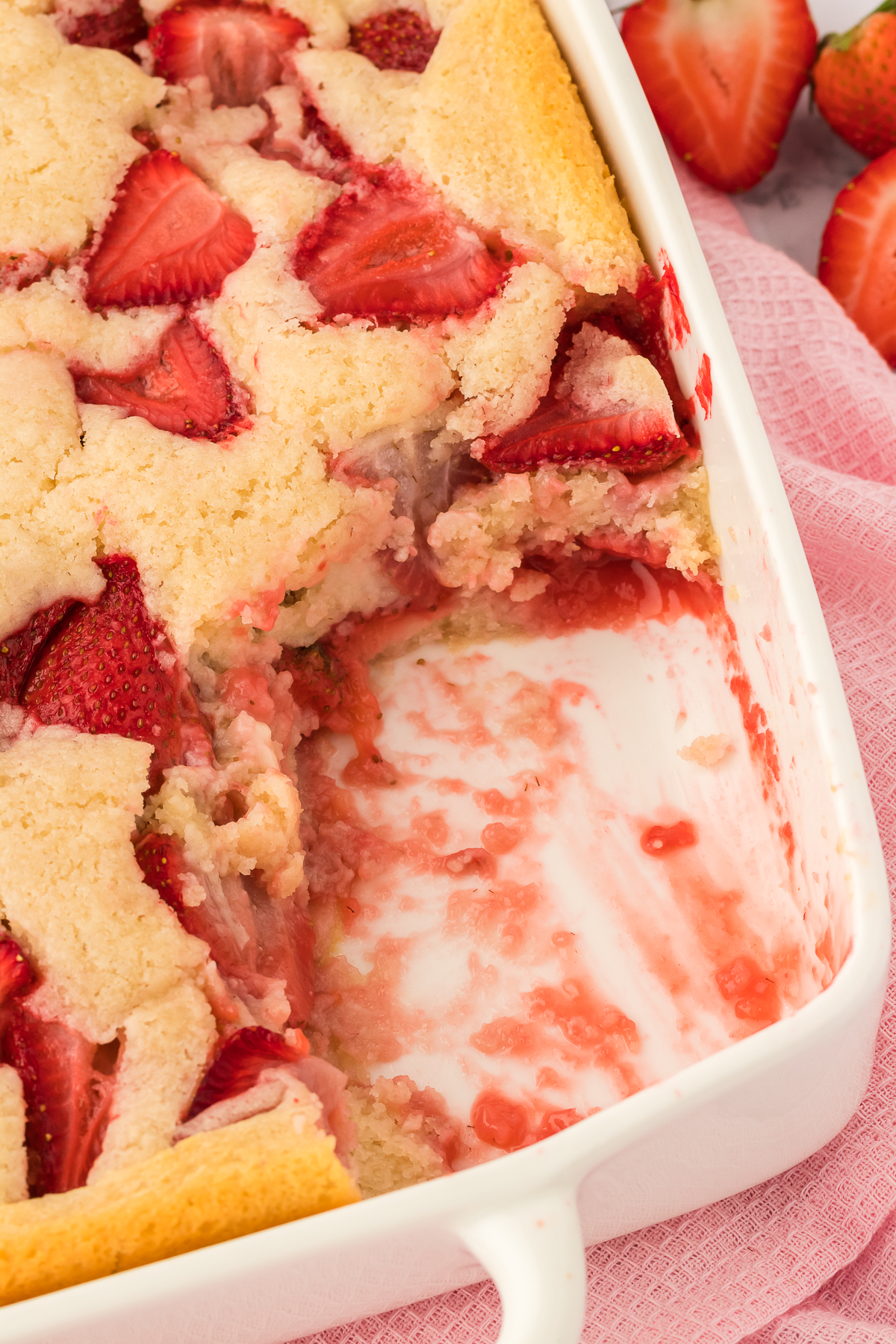 strawberry cobbler in 9x13 inch baking dish with piece missing