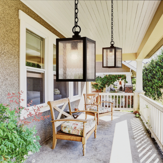 Charming front porch with wooden chairs, floral cushions, and two black rectangular pendant lights hanging from the white ceiling.
